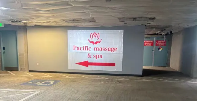 Inside the garage: a banner on the wall reading Pacific massage & spa with a lotus mark and a red arrow pointing toward the suite.